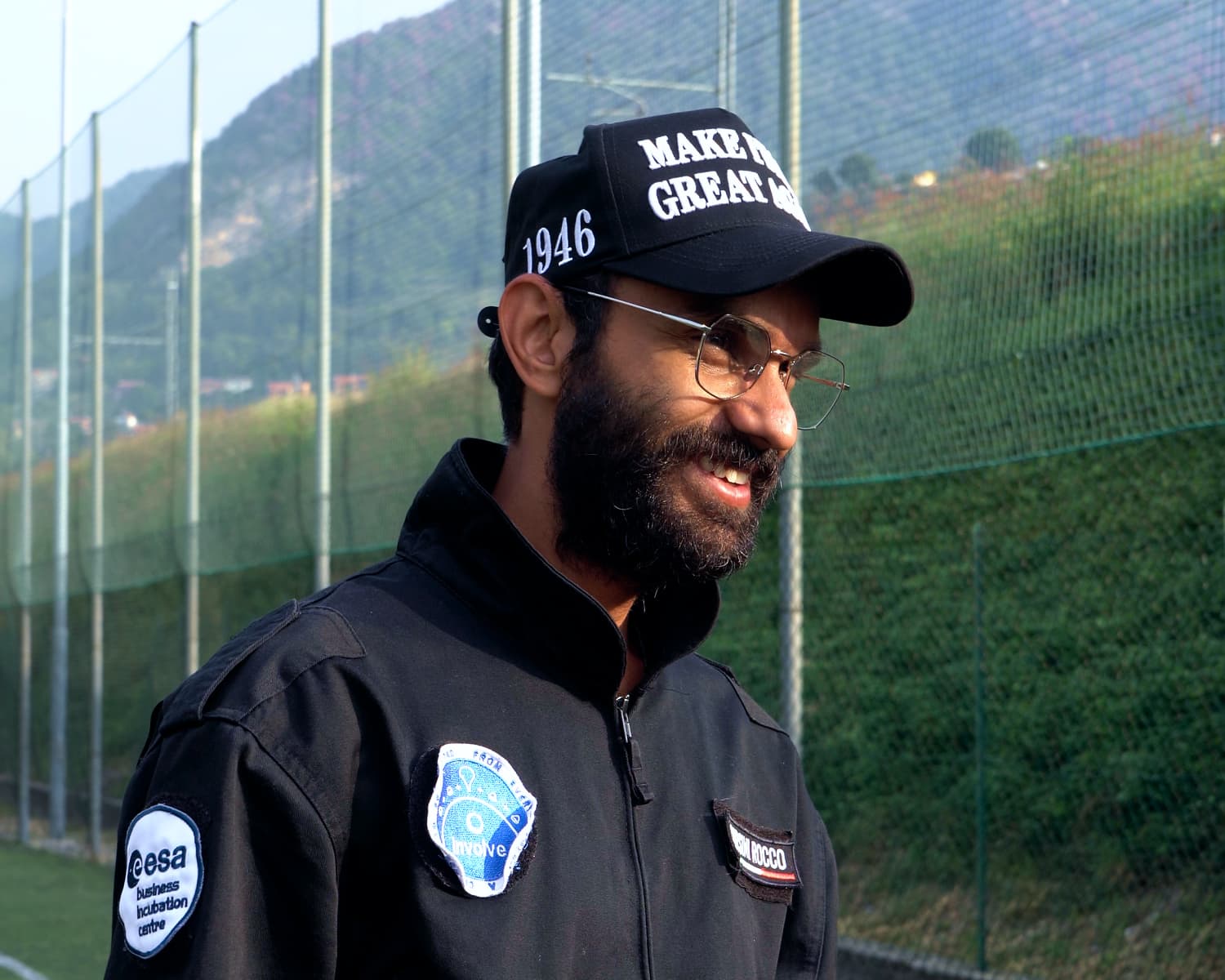 Involve Space team member smiling in a MIGA cap and flight jacket